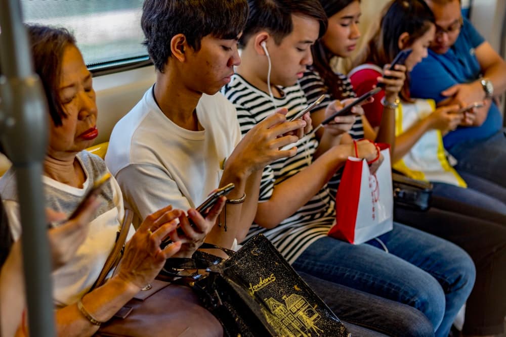 Varias personas consultando el móvil a la vez en un transporte público